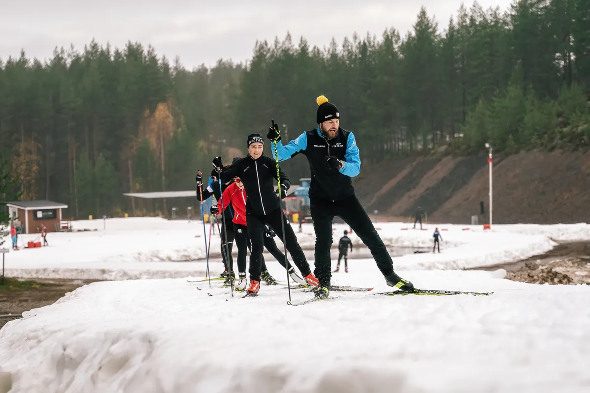 Valmentaja ja hiihtäjät harjoittelevat lumisella ladulla